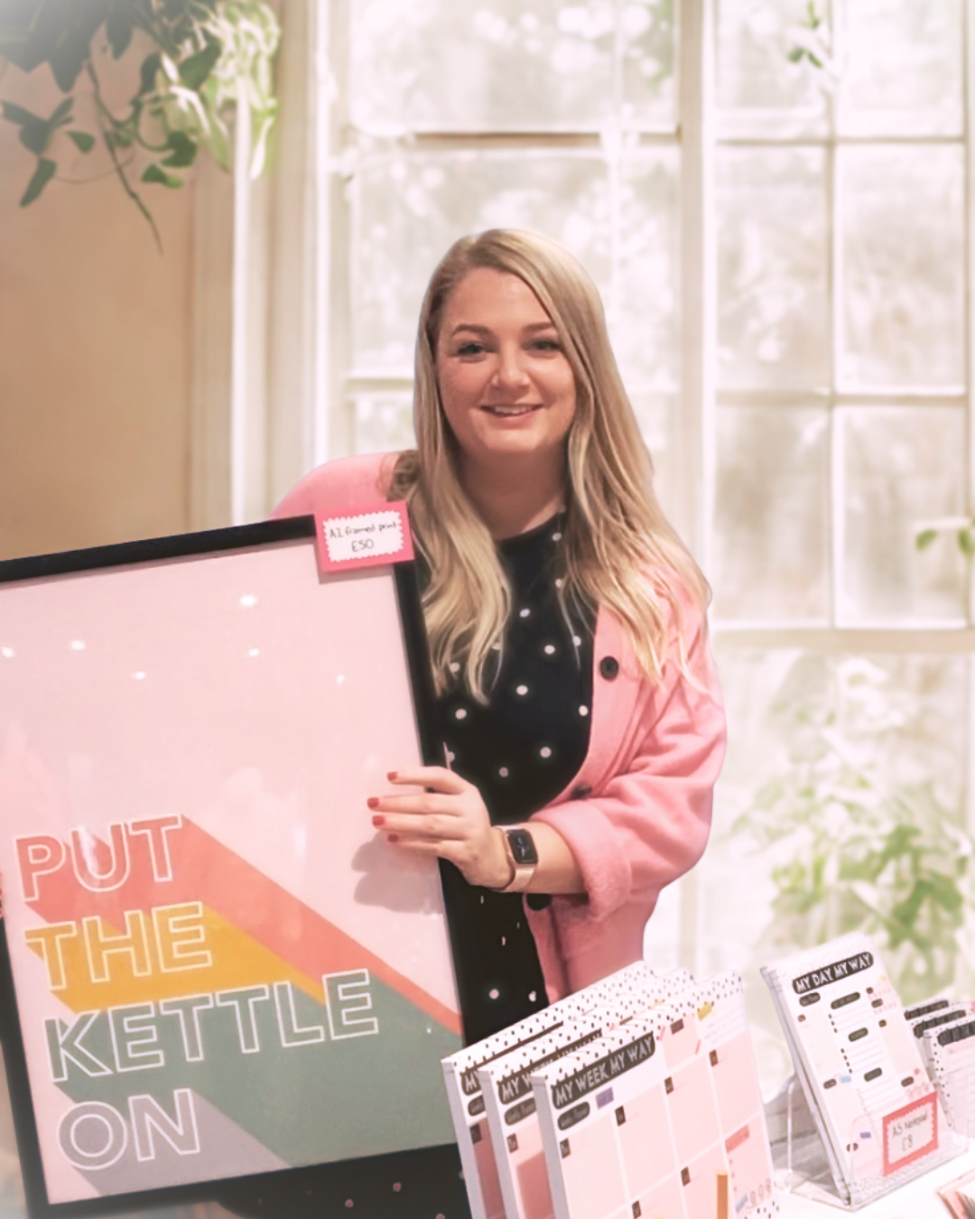 Person holding a framed picture with text and standing next to stationery items.
